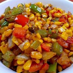 a white bowl filled with corn, peppers and other vegetables on top of a table