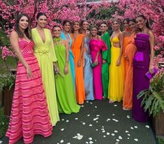 a group of women standing next to each other in front of trees with pink flowers