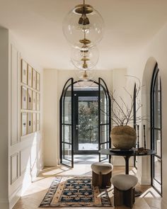 a hallway with an arched doorway and large glass doors leading to another room that has a rug on the floor