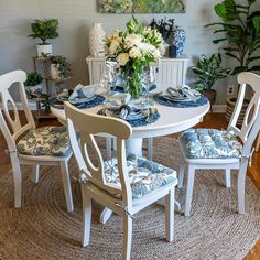 a dining room table set with blue and white china on the table, chairs around it