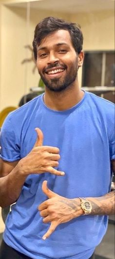 a man in a blue t - shirt is giving the peace sign with his hands