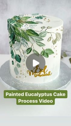 a white cake with green leaves on it and the words painted eucalyptusplus cake process video