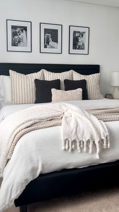 a bedroom with white and black bedding, pictures on the wall above the bed