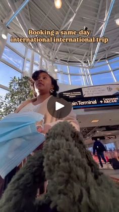 a woman in a white dress is standing inside an airport terminal and looking up at the sky