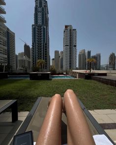 a person sitting in a chair with their legs crossed on the ground and buildings in the background