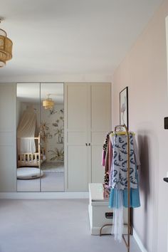 a bedroom with closets and clothes hanging on the rack in front of it, next to a bed