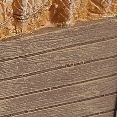 a bird sitting on top of a wooden bench next to a wall with peeling paint