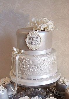 a three tiered wedding cake with white flowers on the top and silver ribbon around it