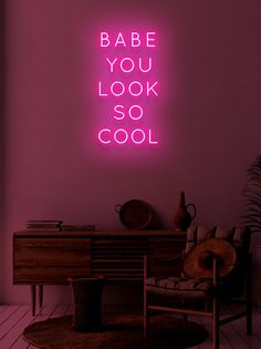 a pink neon sign that says babe you look so cool on the wall above a chair