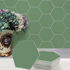 a vase filled with flowers next to green hexagonal tiles