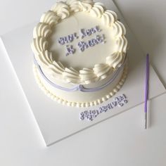 a white cake sitting on top of a table next to a pair of purple scissors