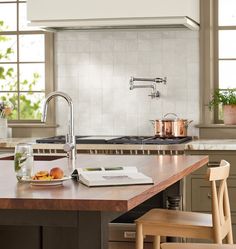 a kitchen with an island, sink and stove in the center is surrounded by wooden chairs