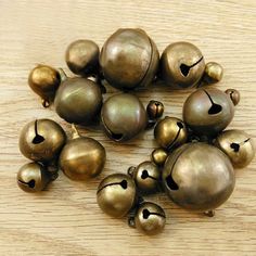 a bunch of bells sitting on top of a wooden table with holes in the middle