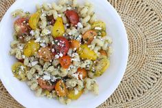 a white bowl filled with pasta salad on top of a table next to a brown mat