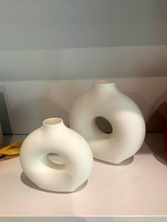 two white vases sitting on top of a table