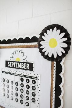 a white and black calendar with a flower on it next to a wall mounted clock