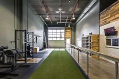 an indoor gym with green carpeting and exercise equipment on the walls, along with large windows that let in natural light