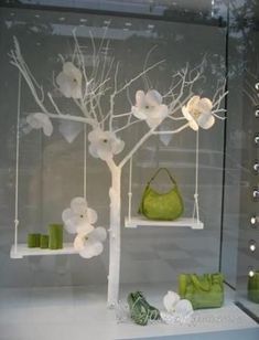 a display case with white flowers and green purses