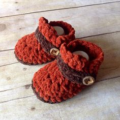 two baby shoes with buttons on them sitting on a wooden floor