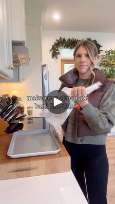 a woman standing in a kitchen holding a spatula