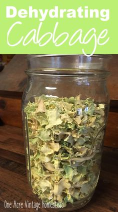 a glass jar filled with green leaves on top of a wooden table and text overlay that reads, dehydrating cabbage