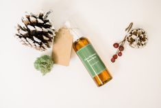 a bottle of essential oil next to some pine cones and other items on a white surface