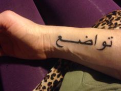 a woman's arm with an arabic writing tattoo on her left wrist and leopard print pants