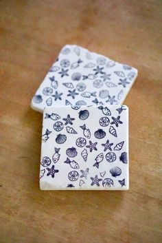 two pieces of blue and white tile with shells on them sitting on a wooden surface