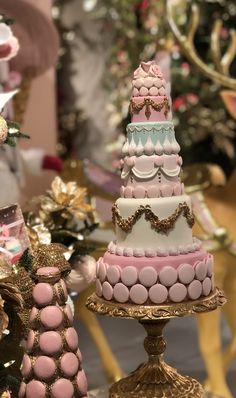 three tiered cake sitting on top of a gold plate next to a christmas tree