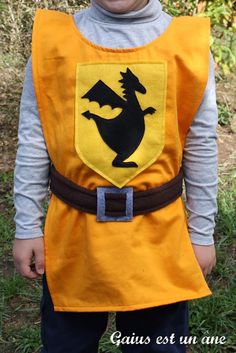 a young boy wearing an orange and black costume with a dragon on it's chest