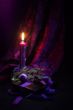 a lit candle sitting on top of a table next to a box with christmas decorations