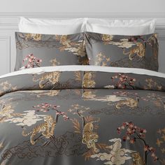 a bed covered in grey and white comforters with tiger designs on the coverlet