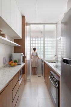 a woman standing in a kitchen next to a stove top oven