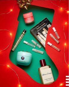 an assortment of beauty products on a green and red surface with christmas lights in the background