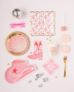 pink and gold party supplies laid out on a white surface