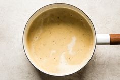 a pot filled with liquid sitting on top of a white counter next to a wooden spoon