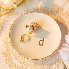 two wedding rings sitting on top of a plate with the letter d next to them