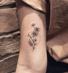 a woman's arm with a small flower tattoo on the left side of her arm