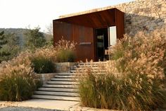 an outdoor area with stone steps, grass and bushes on the side of the building