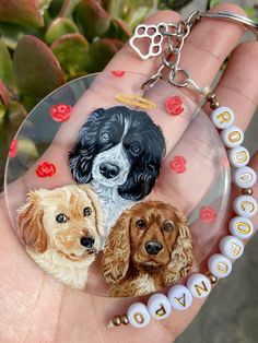 a hand holding a glass keychain with three dogs on it's side