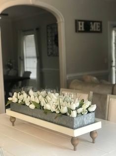 a tray filled with white flowers sitting on top of a table next to a mirror