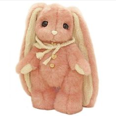 a pink stuffed animal with a scarf around it's neck and ears, sitting on a white surface