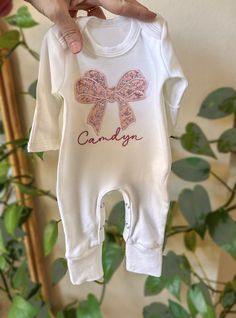 Adorable embroidered rompers are perfect for; announce a baby name,  coming home and newborn photos! baby shower gifts,  Crafted from buttery soft cotton material, it ensures your babies stay cozy and look adorable. This features an white romper, a large embroidery applique bow in blush, mauve and white floral pattern and name in dark pink color under the initial. You can combine it with pink or mauve head bow Customize it with your baby's name, marking this momentous occasion. If you have any c Customizable Pink Onesie For Gift, Personalized Cotton Onesie For Baptism, Personalized Fitted Onesie For Baptism, Embroidered Baby Clothes, Large Embroidery, Girl Coming Home Outfit, Girls Coming Home Outfit, Cricut Craft