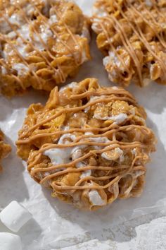 several cookies with icing and marshmallows on top of paper wrappers