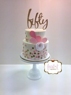 a three tiered cake with polka dots and pink flowers on the top is displayed