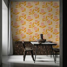 a dining room table with two chairs and a vase on top of it in front of a floral wallpaper