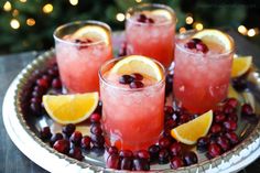 three glasses filled with watermelon and cranberry punch on a plate next to christmas lights