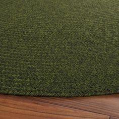 a close up view of a green rug on a wooden floor with wood grained floors