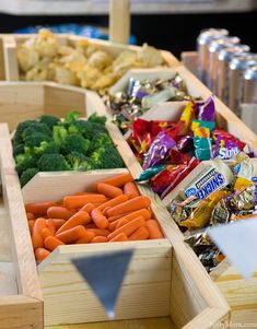 an assortment of fruits and vegetables in wooden boxes on a table with candy bar wrappers