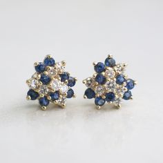 These stunning cluster earrings are made with bright white diamonds and deep blue sapphire gemstones. The vintage clusters are 14k yellow gold and made with threaded backs. These earrings THE perfect gift! Metal: 14K Yellow Gold Diamonds: .42 CTW, SI1, G-H Sapphires: 2 mm each (18) Approx. 2.34 CTW Width: 10.5 MM **Video can be found here: https://blackmarketllc.com/products/14k-yellow-gold-vintage-diamond-and-sapphire-cluster-stud-earrings For a greater selection of jewelry please visit our web Fine Jewelry Yellow Gold Cluster Earrings, Blue Cluster Earrings For Anniversary, 14k Gold Cluster Earrings For Wedding, Stud Earrings Diamond, Art Deco Diamond Rings, Vintage Diamond Rings, White Gold Diamond Rings, Alternative Engagement Rings, Art Deco Diamond